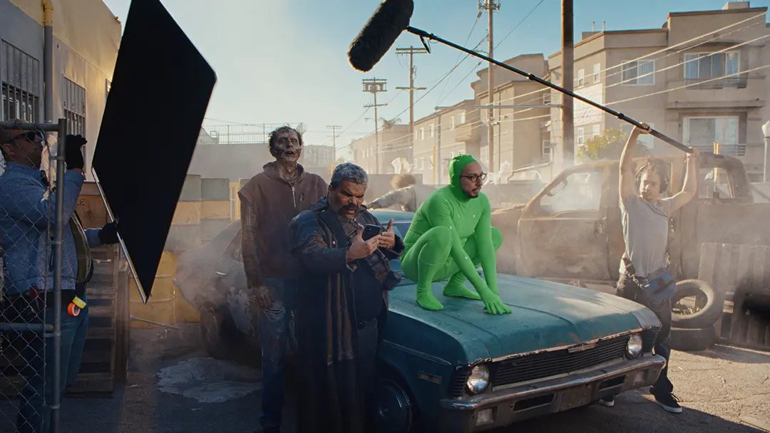 Luis Guzman looks confusedly at his phone while the production of a science-fiction movie comes to a halt around him